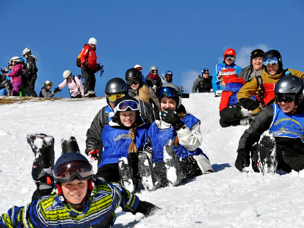 Gruppe liegt und sitzt lachend im Schnee.